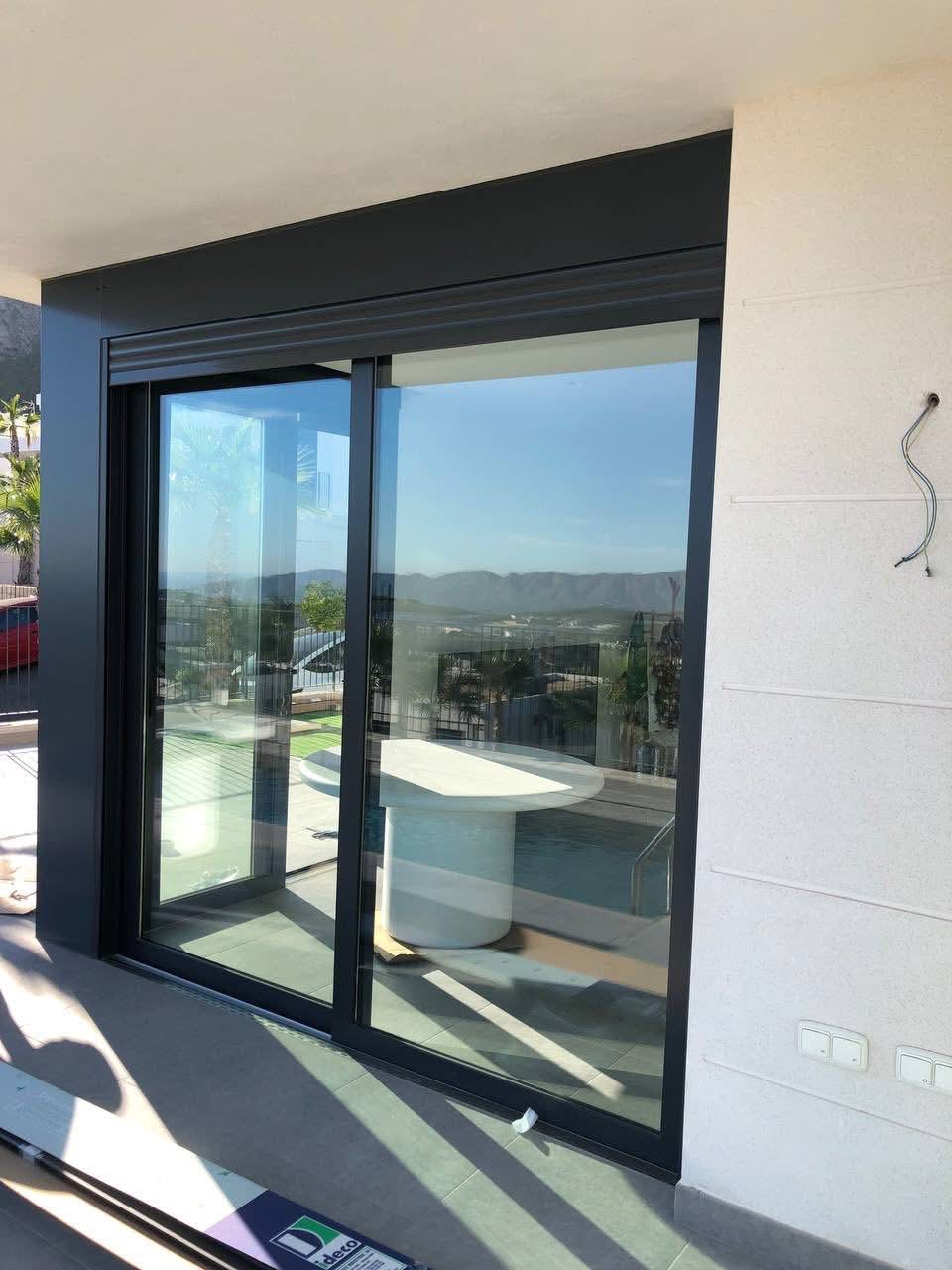 Puerta corredera acristalada de dos hojas con marco antracita en una terraza